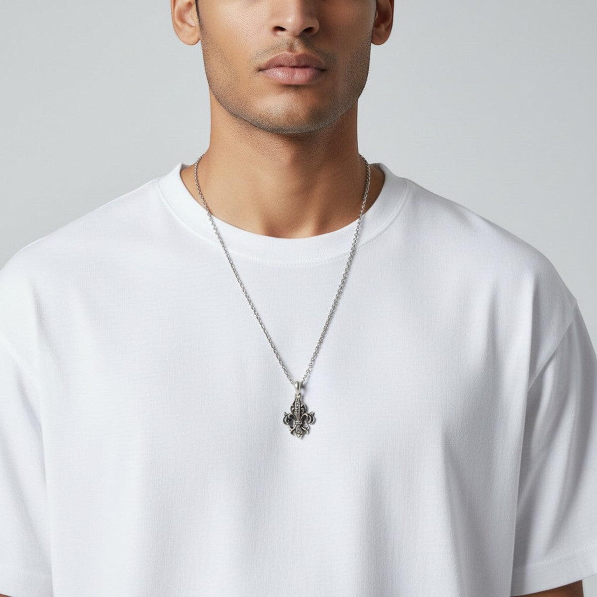 Truelements Jewelry sterling silver fleur-de-lis pendant with black zirconia worn on a chain by a man in a white tee