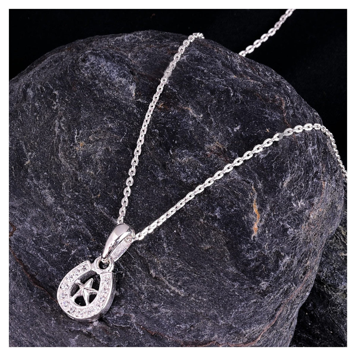 Truelements Jewelry sterling silver horseshoe pendant necklace with a star motif and clear zirconia stones on a rock