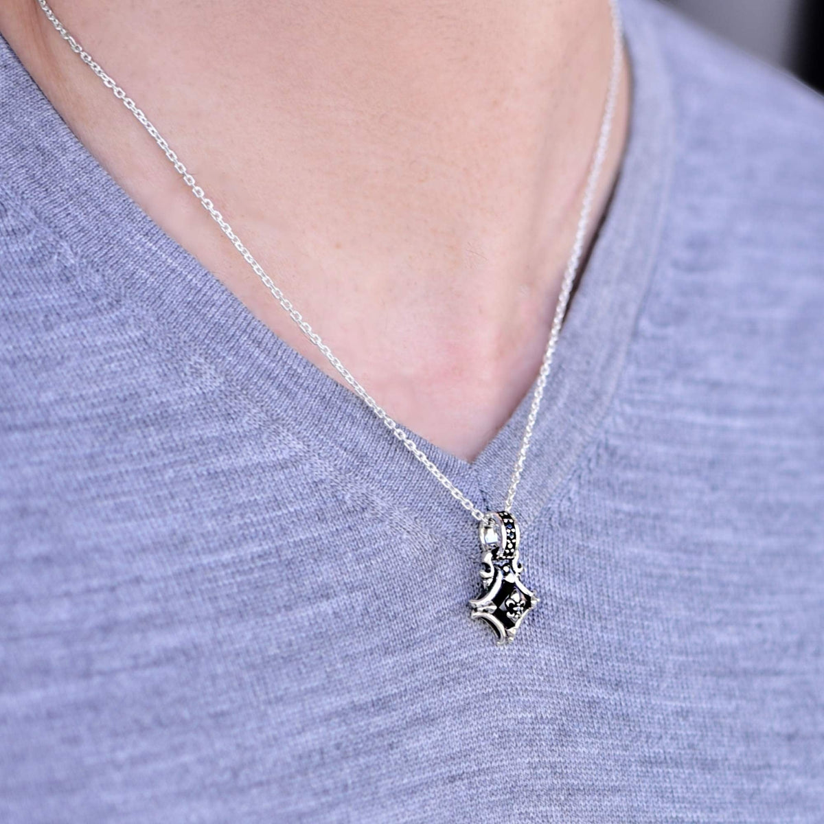 Truelements Jewelry sterling silver cross pendant with black onyx and zirconia on a silver chain worn on a model