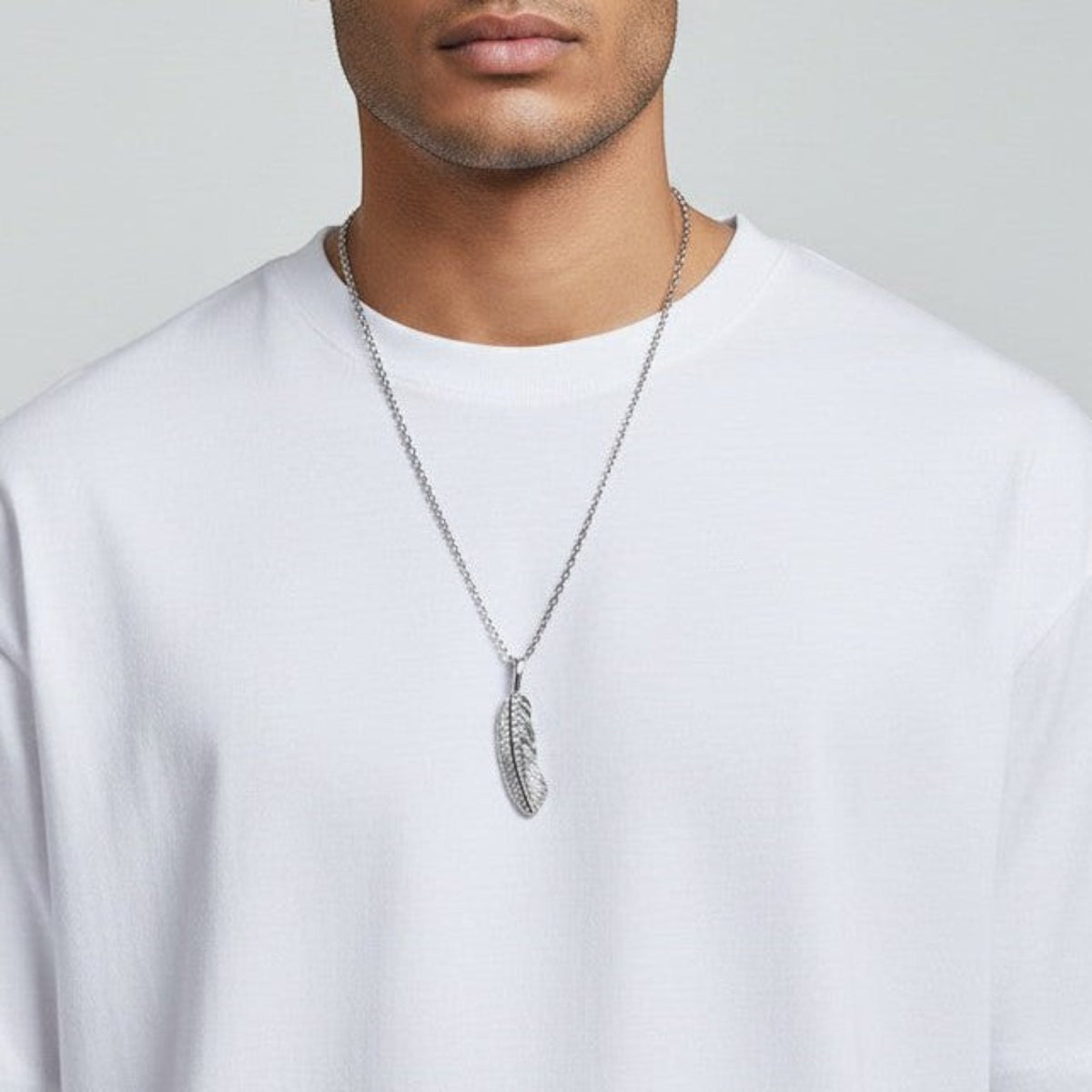 Truelements Jewelry silver 925 feather pendant with clear cubic zirconia on a chain worn by a man in a white shirt