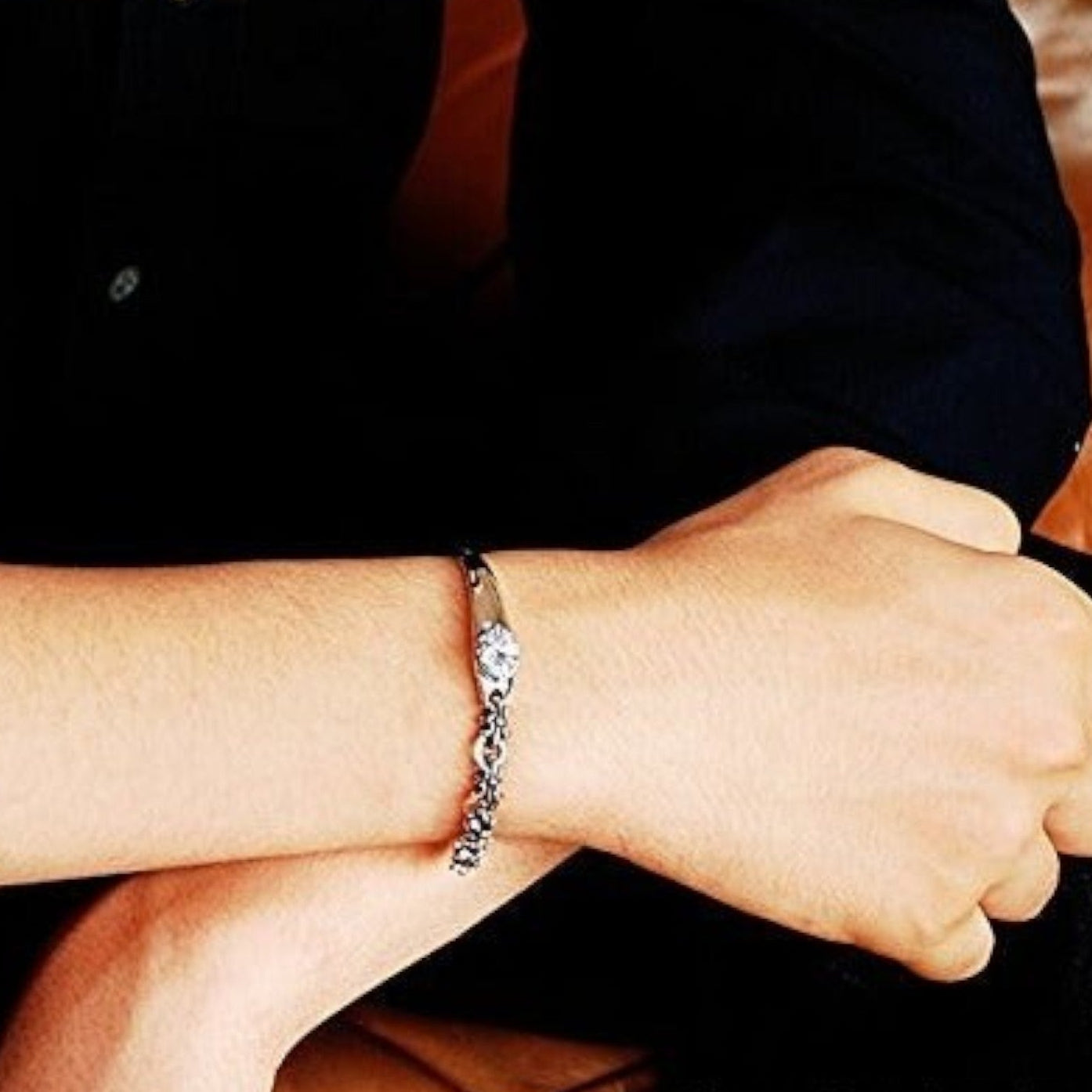 Truelements Jewelry sterling silver bangle with fleur-de-lis motif and clear cubic zirconia on a person's wrist