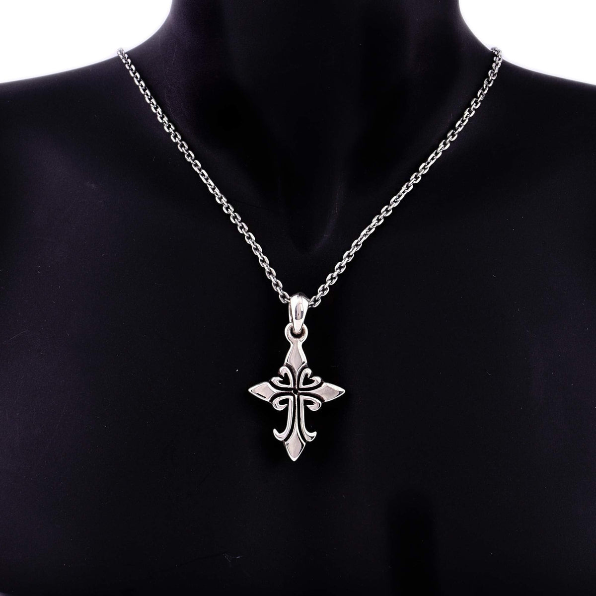 Truelements Jewelry silver 925 fleur-de-lis cross pendant with clear cubic zirconia on a chain against black bust