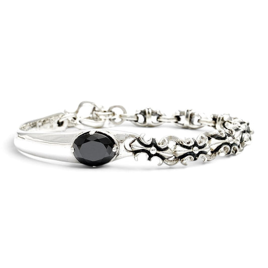 Truelements Jewelry sterling silver bangle featuring a black zirconia stone and ornate fleur-de-lis cross motifs.